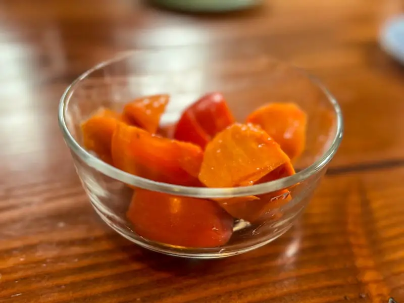 Image of a ripe, Fuyu persimmon cut up in a bowl.