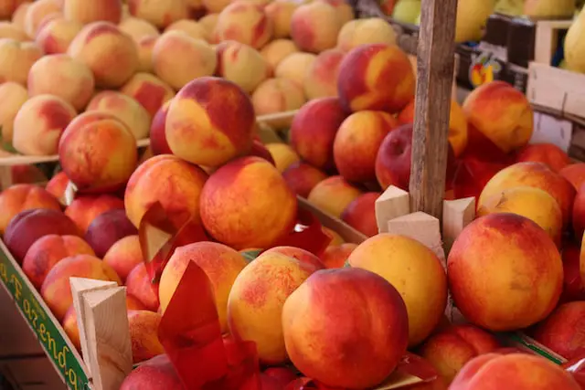 Image of ripe peaches in crates at a farm stand.