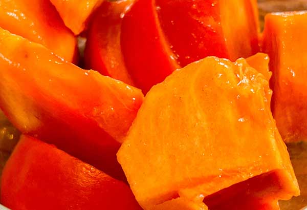 Closeup image of a bright orange, juicy, peeled, and cut-up 'Fuyu' persimmon.